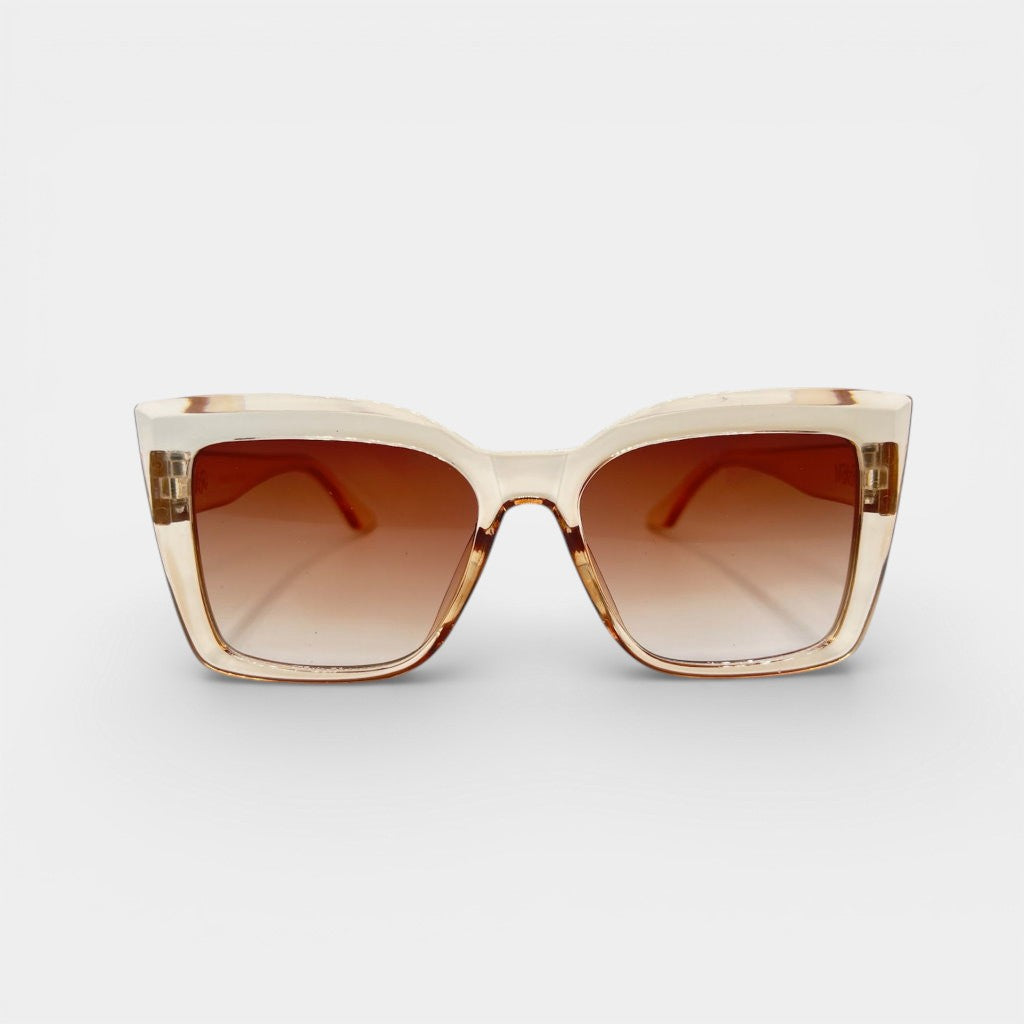 Sunglasses with a beige frame and brown lenses on a grey background