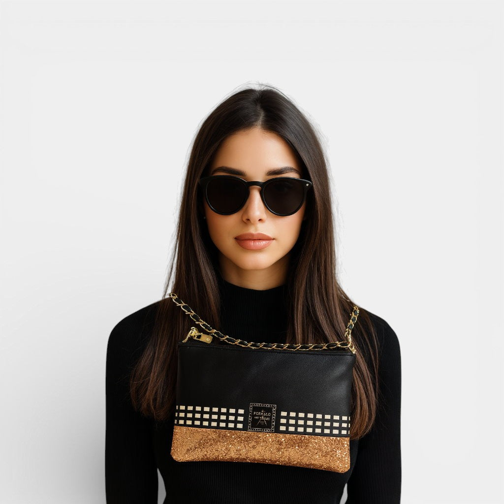 Woman wearing sunglasses and a black top with a gold crossbody pouch over her shoulder.